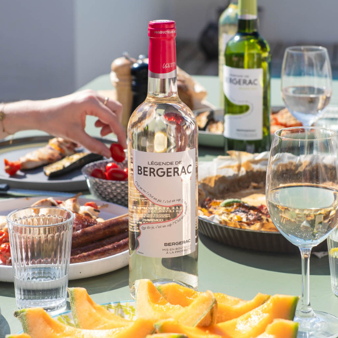 Légende de Bergerac Rosé AOP Bergerac sur table de déjeuner d’été avec melon et grillades