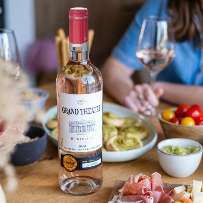 Bouteille de Grand Théâtre Bordeaux rosé avec planche de charcuterie, tomates cerises, feuilletés au pesto et guacamole