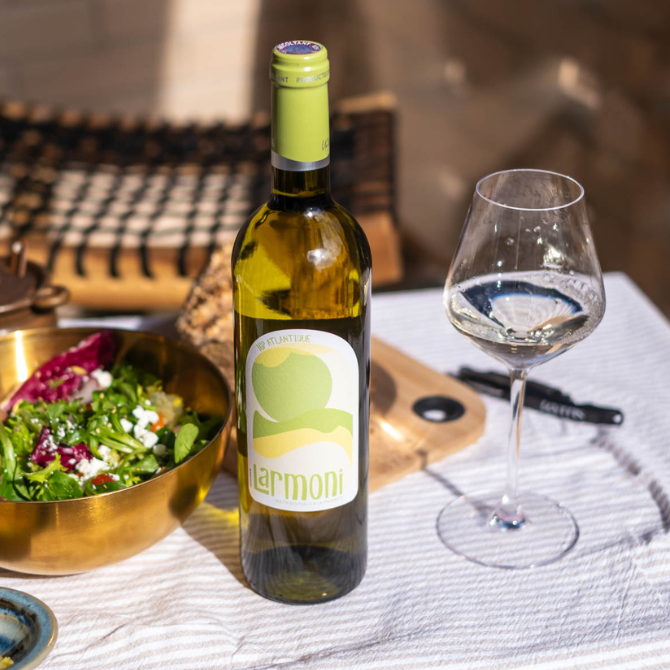 Bouteille et verre de Larmoni IGP Atlantique Blanc sur table de déjeuner estival avec salade fraîche