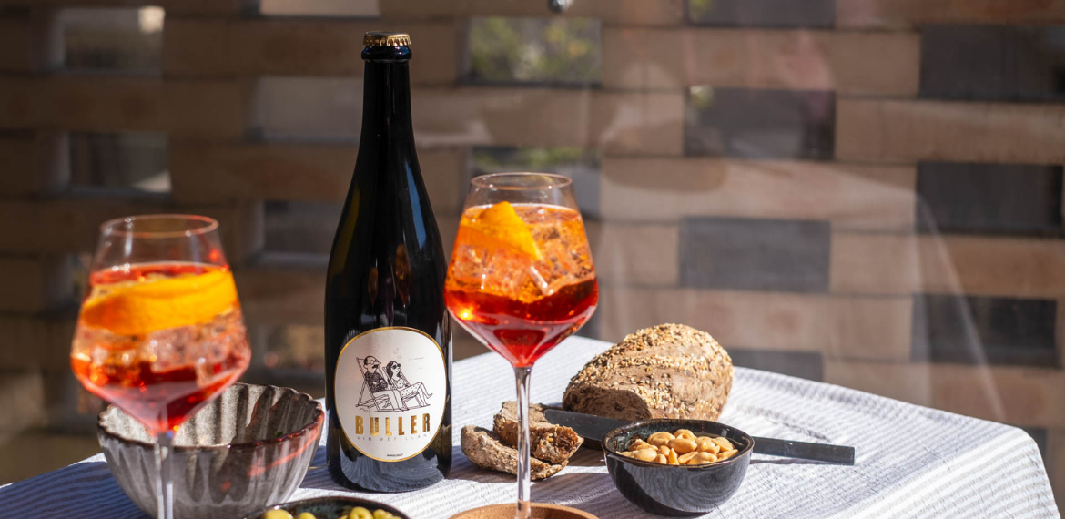 Cocktail spritz préparé avec le vin blanc pétillant Buller sur une table d’apéritif