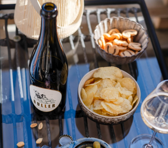 Bouteille de vin blanc pétillant Buller sur une table d’apéritif avec chips et olives