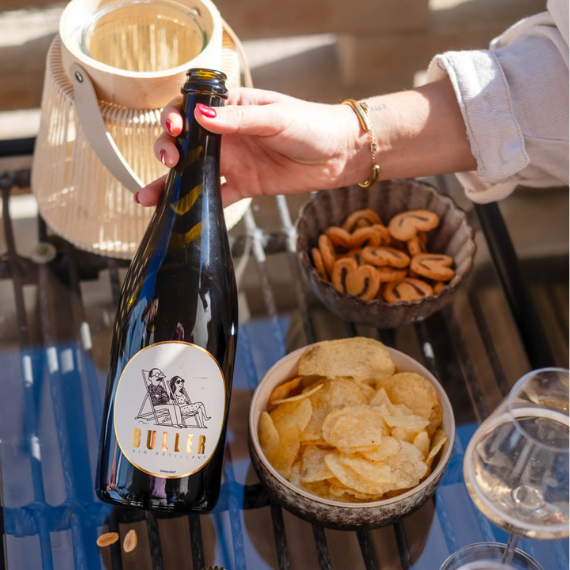 Bouteille de vin blanc pétillant Buller sur une table d’apéritif avec chips et biscuits